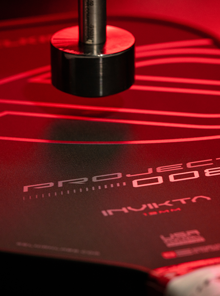 Close-up of the Selkirk Sport Project 008 pickleball paddle featuring the bold Pureform technology design, highlighted under dramatic red lighting to showcase precision engineering and premium surface texture.