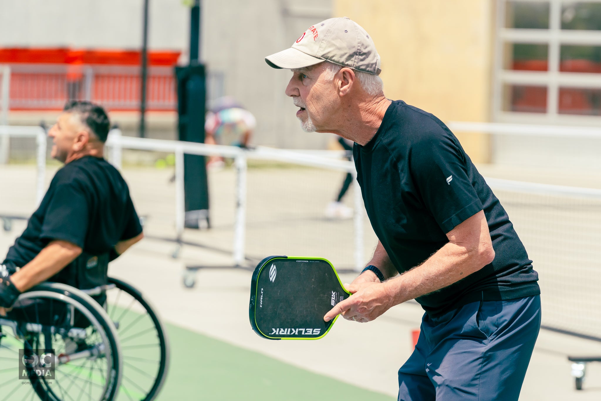A man prepares to receive a pickleball shot, holding a SLK Halo paddle, during a Pickleball for Parkinson's event.