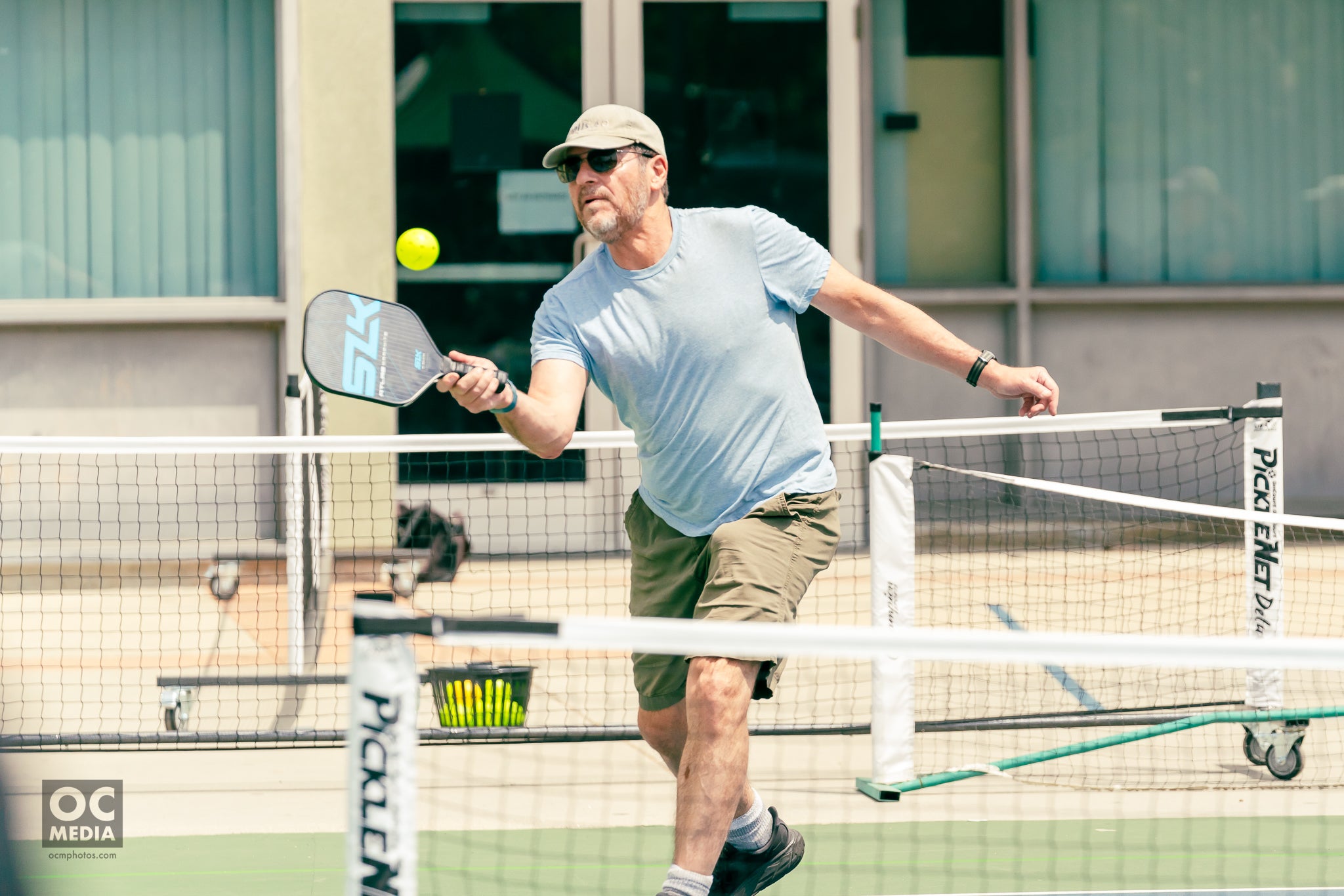 A man playing pickleball, hitting a ball with a paddle on a court.