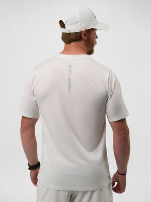 Man seen from back wearing white athletic tee with vertical SELKIRK logo and white cap