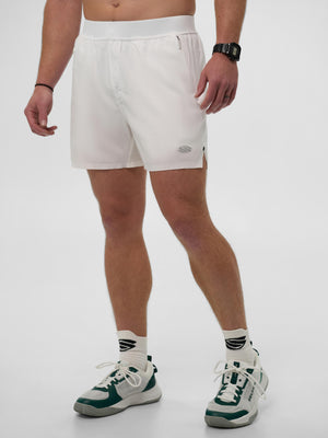 Male model wearing white athletic shorts with zip pockets and small thigh logo, white socks and green-and-white sneakers.