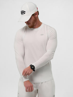 Male model wearing white long-sleeve performance shirt and white cap with S logo, adjusting sleeve; black digital watch.