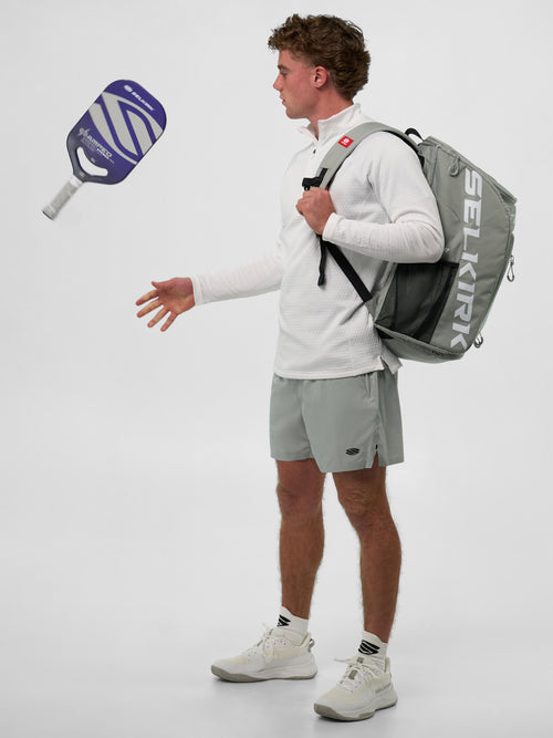 Model wearing the Men's Pro Line 1/4 Zip Pullover, holding a pickleball paddle and backpack.