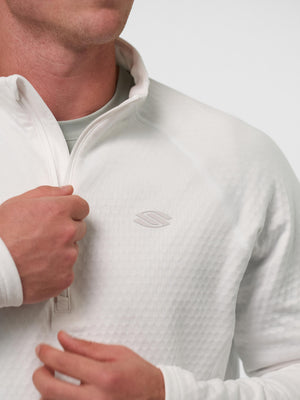 Man adjusting white textured quarter-zip pullover with small embossed chest logo visible
