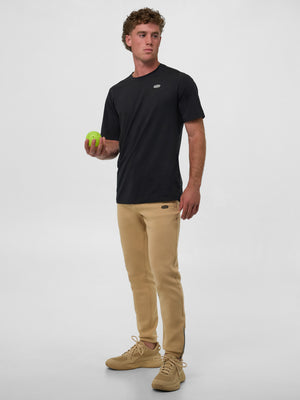 Model wearing Blackout Men's Pro Line Athletic Short Sleeve shirt and beige joggers, holding a green ball