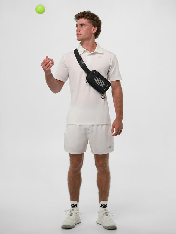 Model wearing Men's Pro Line Performance Polo in Chalk, holding a pickleball.