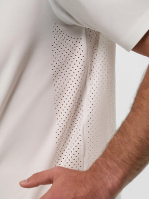 Close-up of cream short-sleeve shirt's perforated side panel with a forearm and hand at the hip.