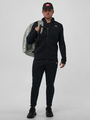 Model wearing the Men's Pro Line Full Zip Jacket in black, holding a backpack.