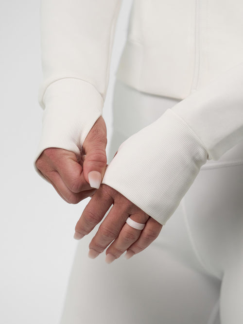 Close-up of hands adjusting the cuffs of the Women's Pro Line Full Zip-Up Cropped Jacket in Chalk.