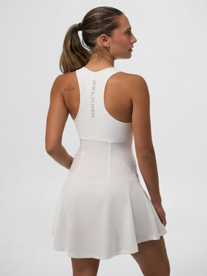 Woman wearing a white racerback tennis dress with SELKIRK logo down the center back, viewed from behind