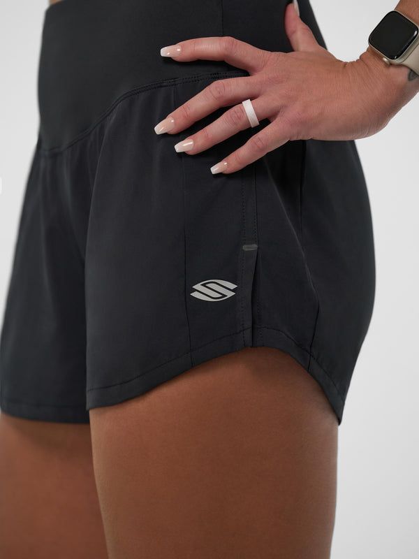Close-up of women's black pickleball shorts with logo and hand showing ring