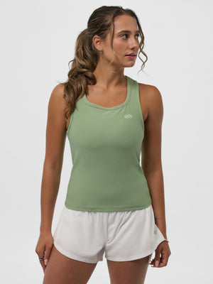 Woman wearing sage-green athletic tank top and white running shorts, standing with hands at her sides.