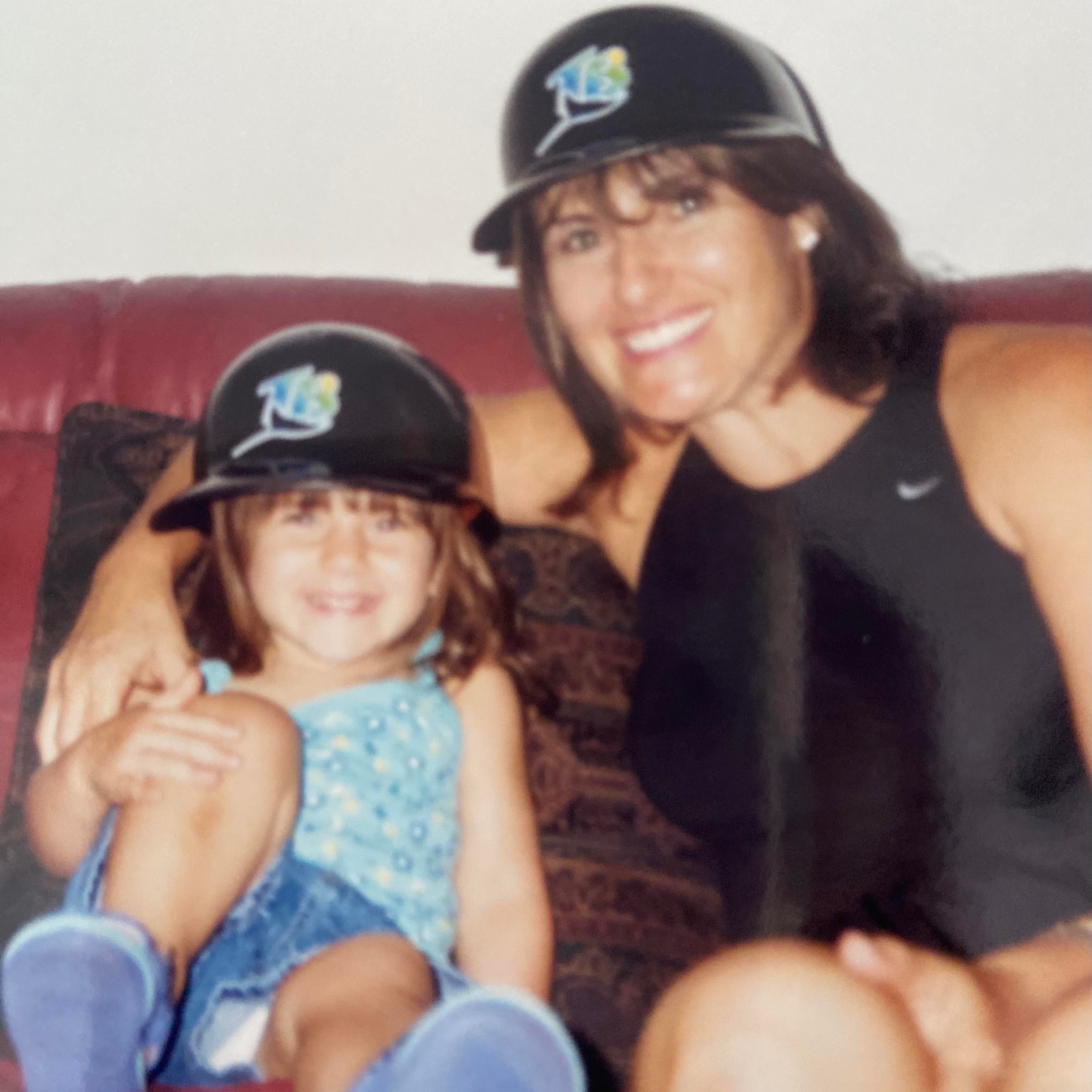 Pickleball pro Rachel Rohrabacher as a child with her mother, both wearing hats, sitting on a couch.
