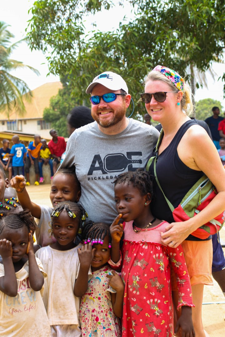 Small children gather around two adults for a photo at a school in Africa. 