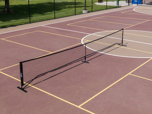 SLK Pro Portable Pickleball Net set up on a pickleball court with visible lines and shadows.