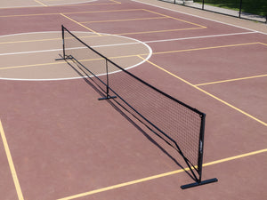 SLK Pro Portable Pickleball Net set up on a court with a brown surface and yellow lines.