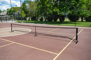 SLK Pro Portable Pickleball Net set up on a court with a black frame and netting.