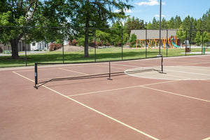 SLK Pro Portable Pickleball Net set up on a court with playground in the background