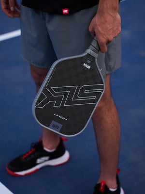 Person holding the SLK HALO Control Max pickleball paddle in blue on a court.
