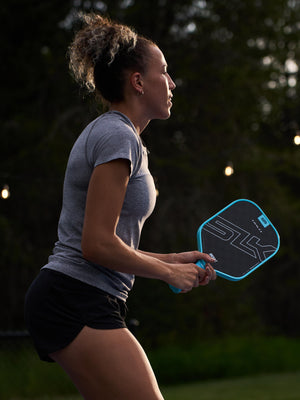 A woman holding the SLK HALO Control Max pickleball paddle, preparing to hit a ball.