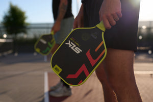 SLK Nexus Max pickleball paddle in Citron color, held by a player on the court