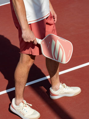 Player walking on a clay-red court with a Boomstik Canyon Clay paddle