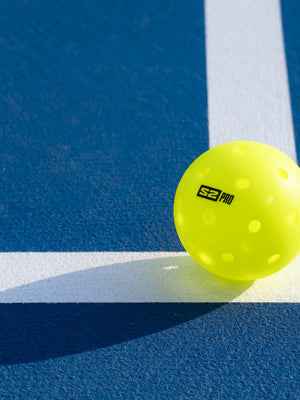 S2 Pro Ball on the line of a blue pickleball court