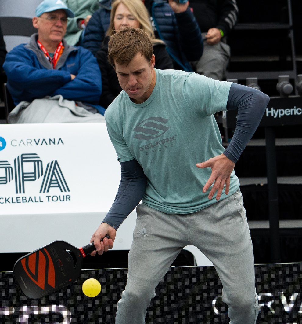 Todd Fought playing pickleball, wearing a teal shirt and gray pants, preparing to hit a ball.