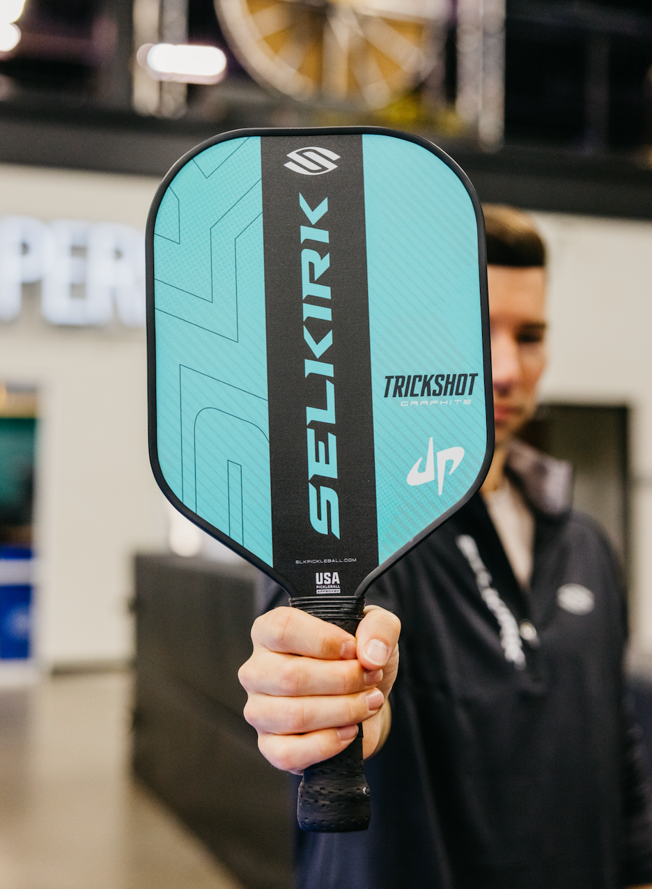 Cory Cotton holding the SLK by Selkirk x Dude Perfect Trickshot paddle, featuring a turquoise and black design.