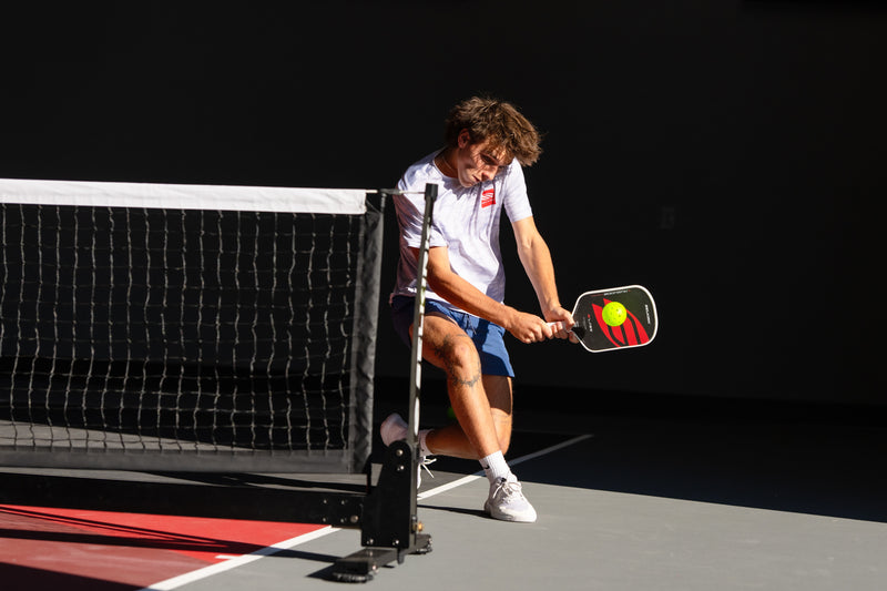 Person playing pickleball on a court with a black background