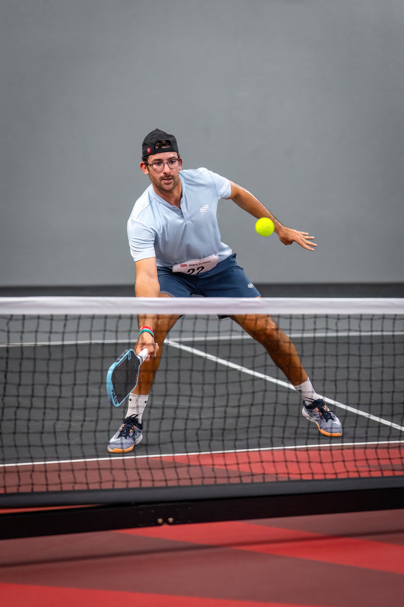 Man playing pickleball on a court with a gray background