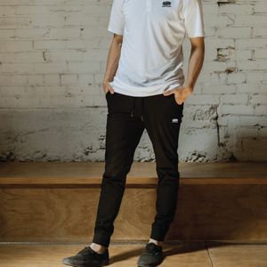 A model wearing Selkirk TruWear Men's Peak Lifestyle Performance Joggers in black, paired with a white polo shirt.