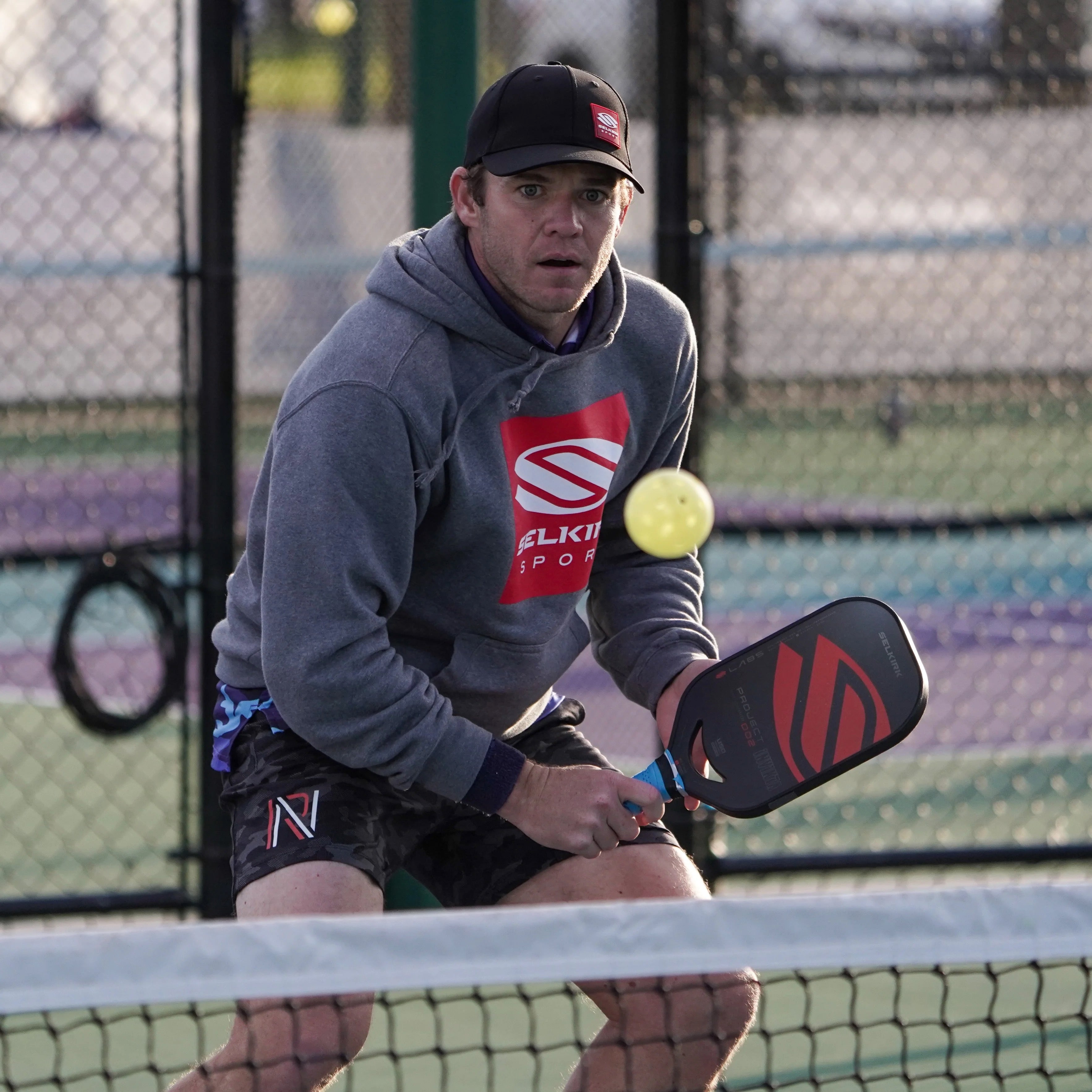 Photo of Selkirk Sport pickleball paddles and balls lying down on a pickleball court.