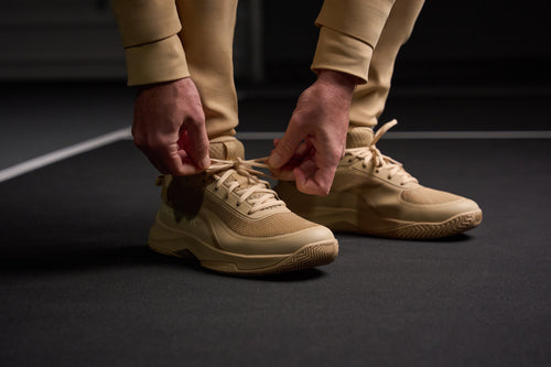 A person tying the laces of Men's CourtStrike Pro Pickleball Shoes in Sandstone color.