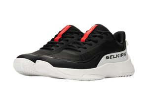 Black low-top athletic sneakers with white chunky sole and red tongue tab branded 'SELKIRK'.