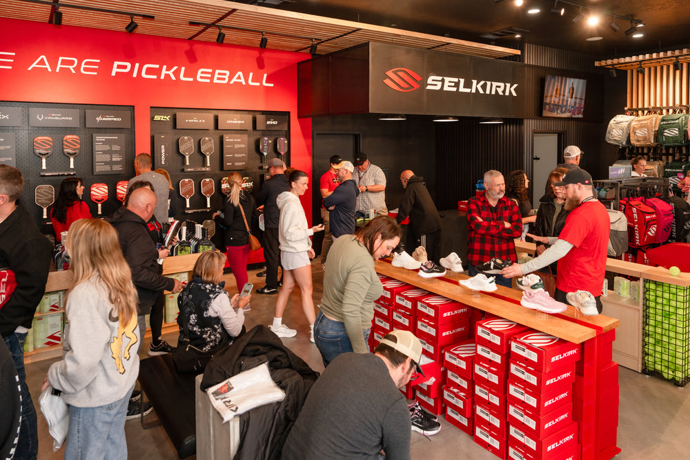 SELKIRK pickleball store interior with customers browsing paddles and shoes; wall sign reads ARE PICKLEBALL