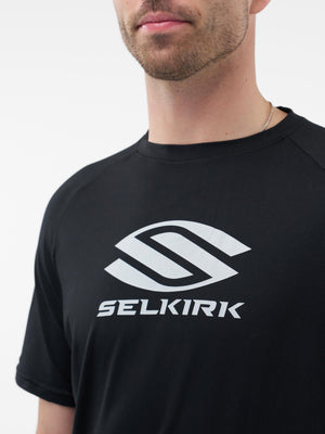 Man wearing black t-shirt with large white SELKIRK logo centered on chest, cropped at the chin