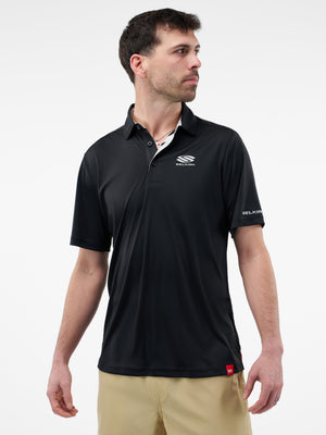 Male model wearing black polo with SELKIRK logo on chest and sleeve