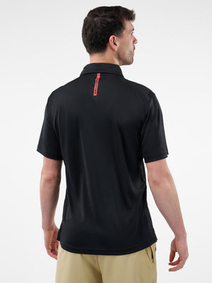Man viewed from back wearing a black short-sleeve polo with a vertical red tag reading STRETCH and tan shorts.