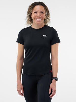 Smiling woman wearing black athletic T-shirt and leggings with white SELKIRK logo on chest, smartwatch on left wrist