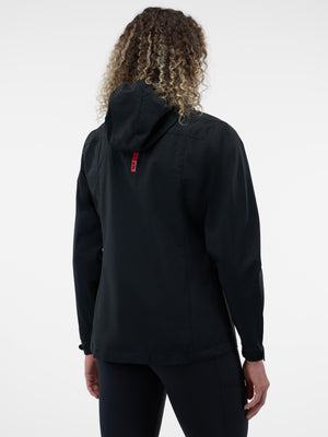 Back view of person wearing black hooded jacket with red vertical tag at upper back and curly hair.