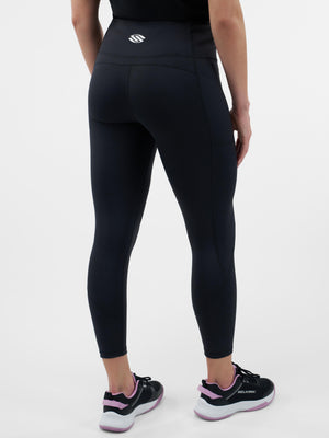 Back view of model wearing black high-waist ankle leggings with side pocket; shoes show 'SELKIRK' logo.