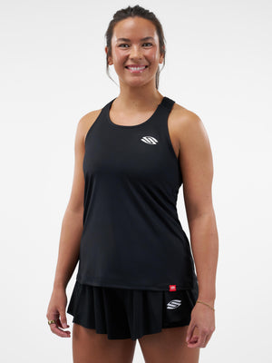 Smiling woman wearing black athletic tank top and pleated tennis skirt with white S logos, standing facing camera.