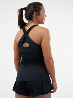 Back view of woman wearing black athletic tank with crossed straps and keyhole back, and black shorts.