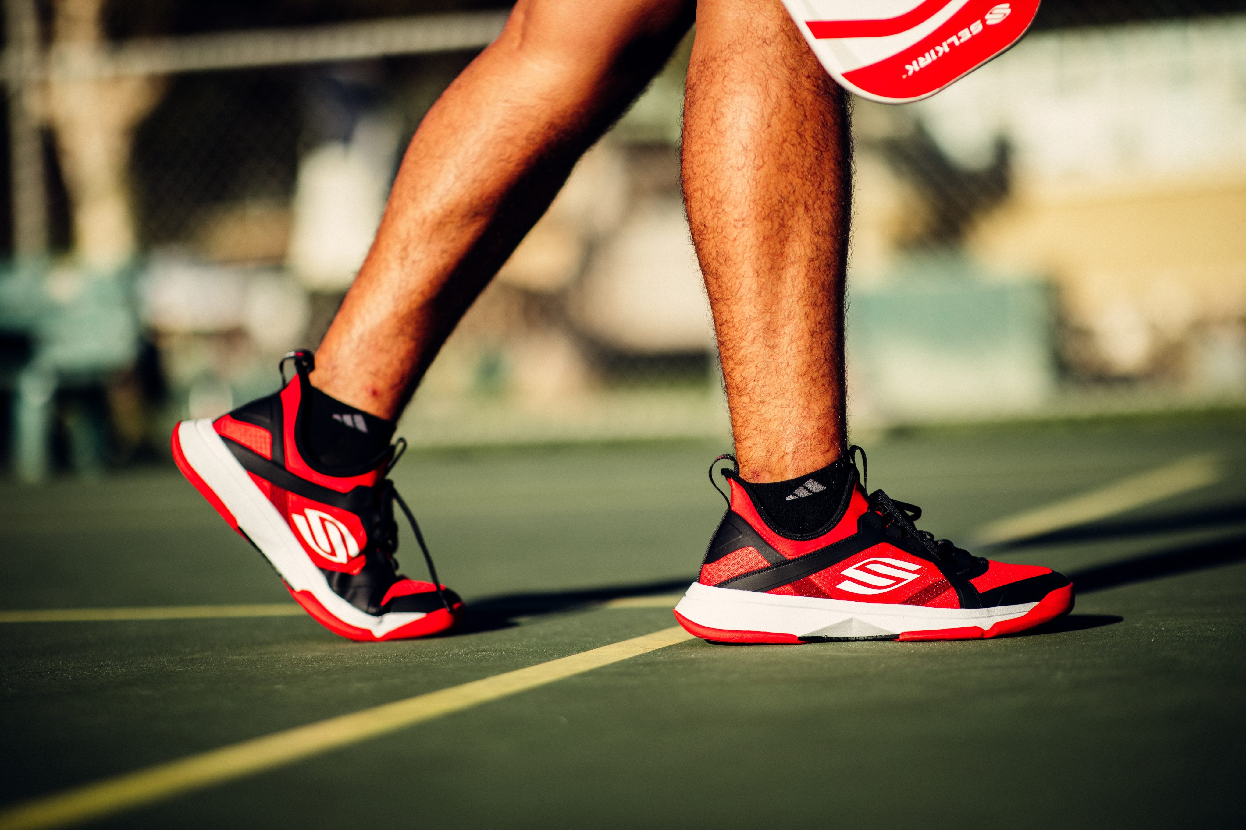 Selkirk LABS red and black pickleball shoes on a court, showcasing their design and grip features.
